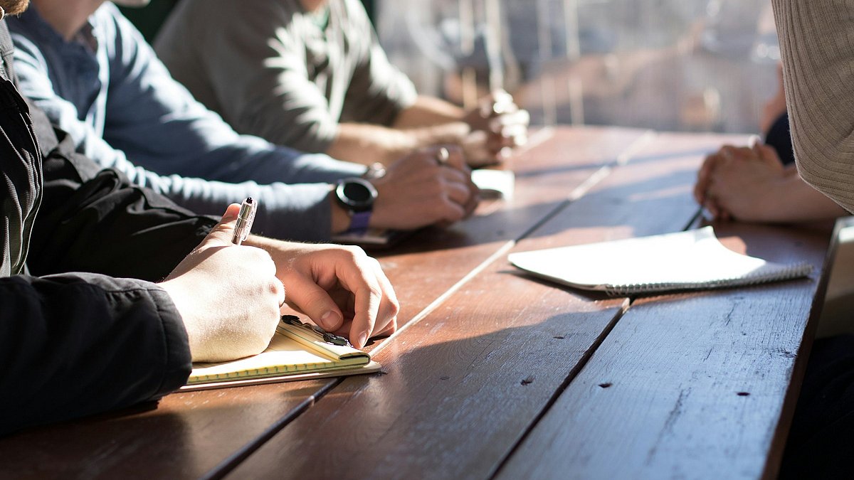 Menschen sitzen an einem Tisch und tauschen sich aus
