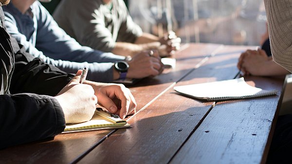 Menschen sitzen an einem Tisch und tauschen sich aus