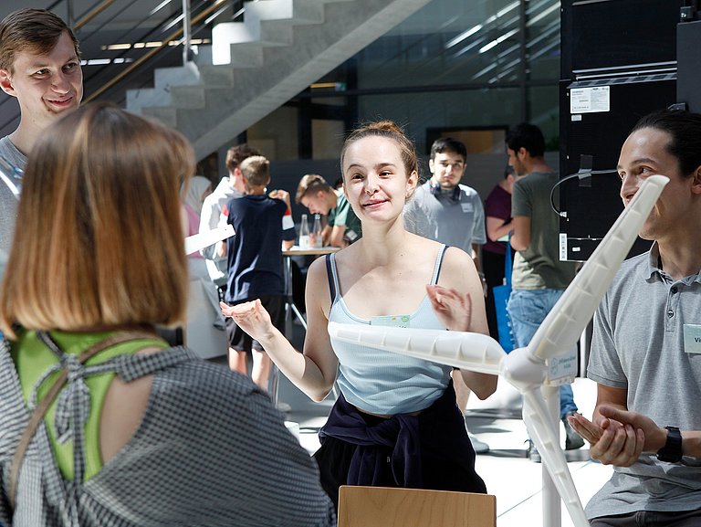 Personen an einem Stand erklären Zuschauenden etwas zu einem Windkraftmodell