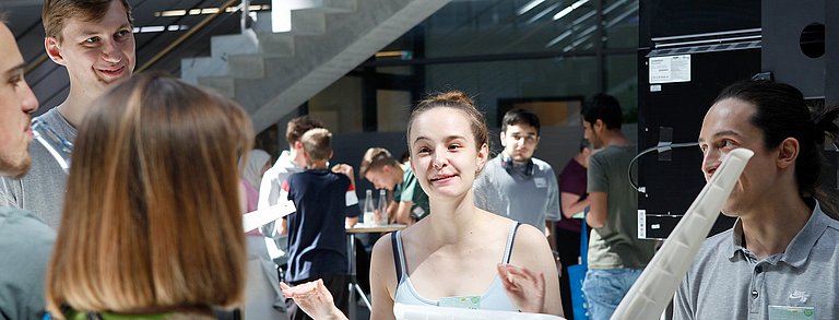 Personen an einem Stand erklären Zuschauenden etwas zu einem Windkraftmodell