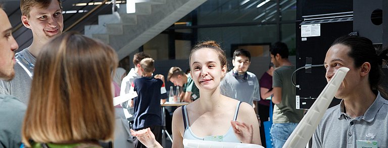 Personen an einem Stand erklären Zuschauenden etwas zu einem Windkraftmodell