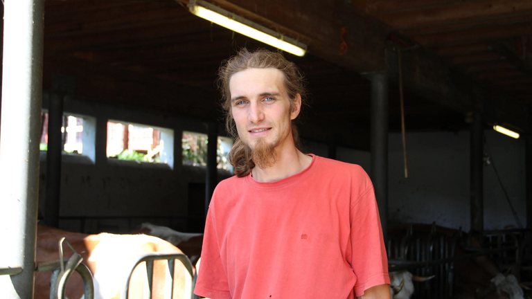 Ein Porträtfoto eines Landwirts im Kuhstall.