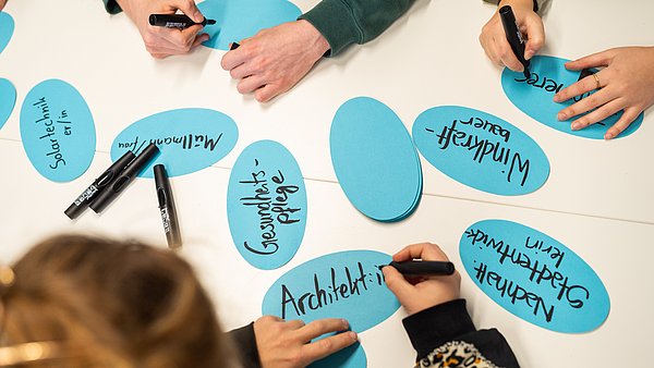 Hände, die grüne Berufe auf Kärtchen schreiben