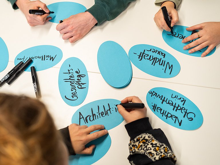 Hände, die grüne Berufe auf Kärtchen schreiben 