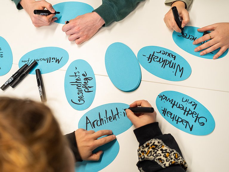 Hände, die grüne Berufe auf Kärtchen schreiben 