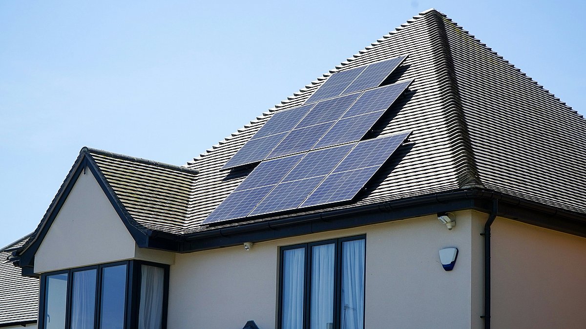 Hausdach mit installierter Photovoltaikanlage aus mehreren Solarmodulen, die auf der sonnigen Dachfläche Strom aus Sonnenenergie erzeugen.
