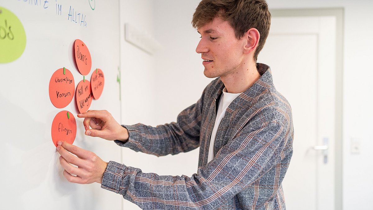 Ein Mitglied des Jugendrats bringt beschriftete Karten an eine Pinnwand an.