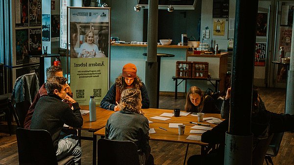 Eine Gruppe sitzt an einem Tisch zusammen und brainstormt