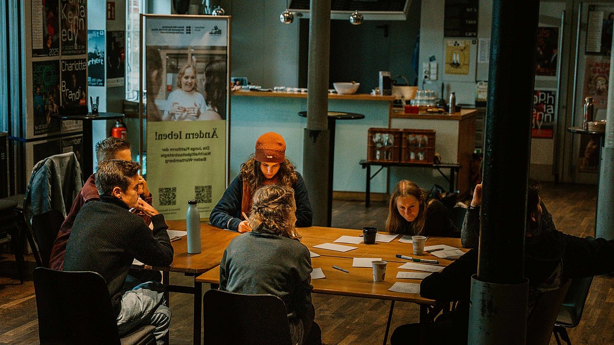 Eine Gruppe sitzt an einem Tisch zusammen und brainstormt