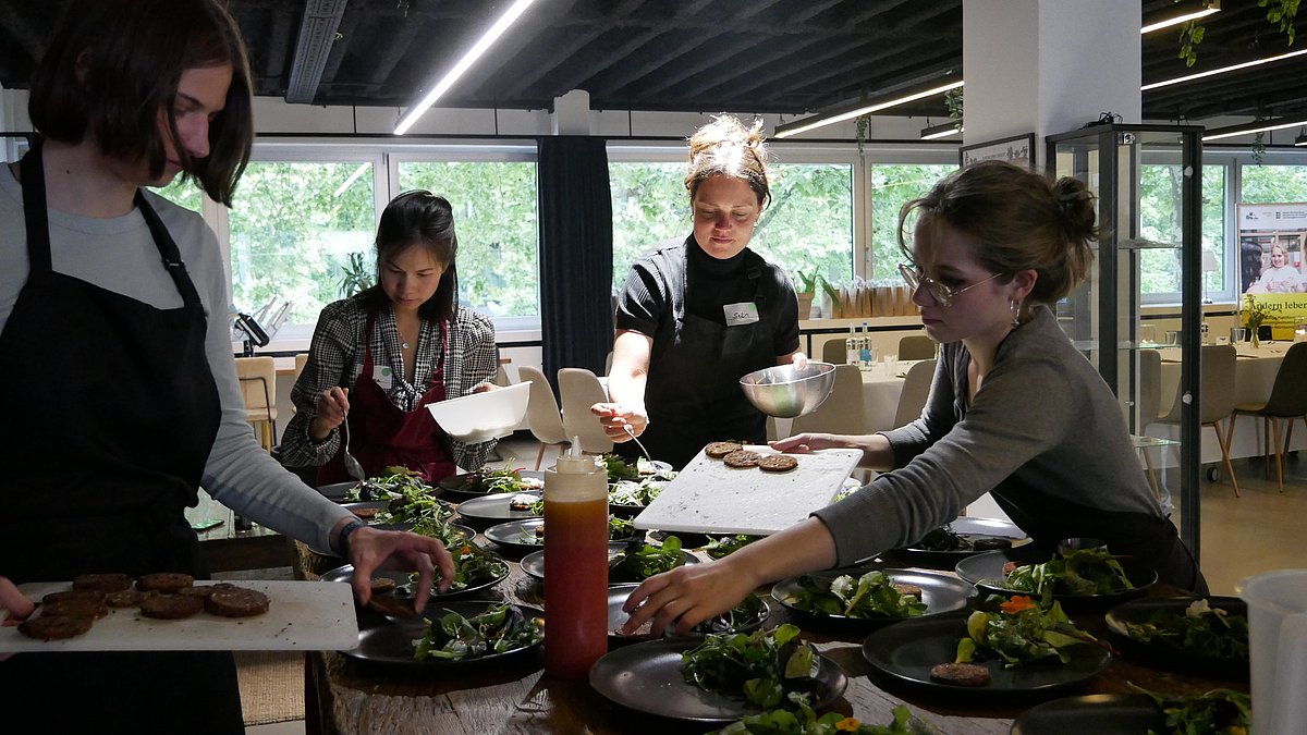 Menschen in einem Kochkurs stehen um eine Kochinsel