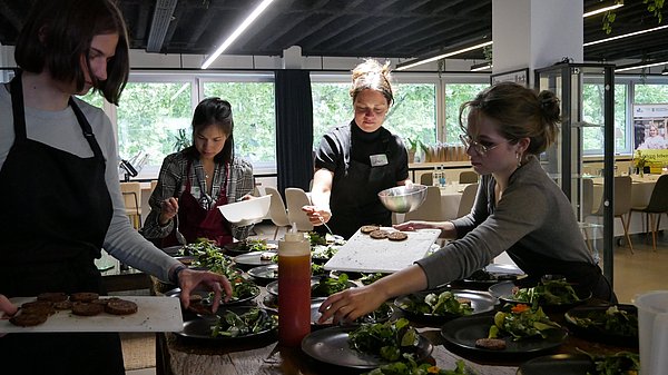 Menschen in einem Kochkurs stehen um eine Kochinsel
