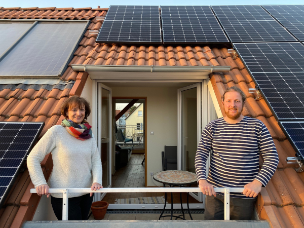 "plan b: Sparsam und sauber: Strom aus der Nachbarschaft": Ursula Röper und Andreas Gißler stehen auf einem Dachbalkon, der von Solarpanels umgeben ist, und lächeln in die Kamera.