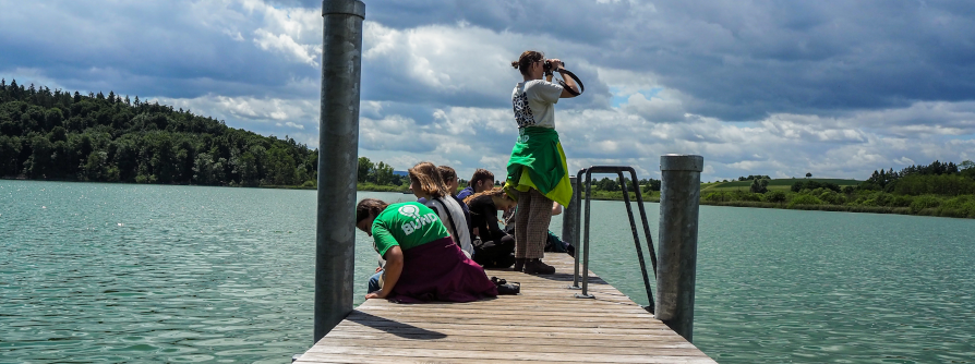 Junge Personen auf einem Steg über einem See